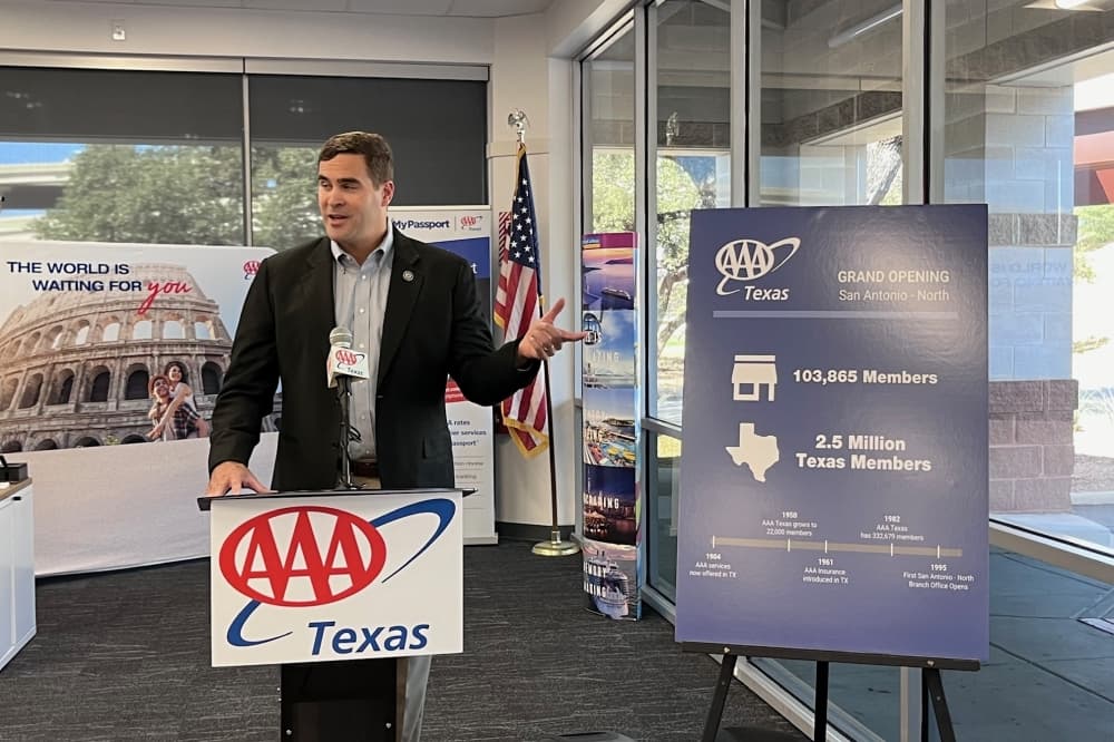 a man speaks from a podium that says AAA Texas
