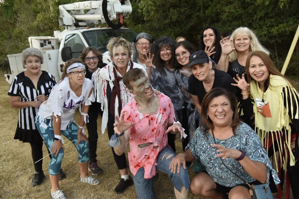 A group of adults smile for a photo dressed in Halloween costumes.