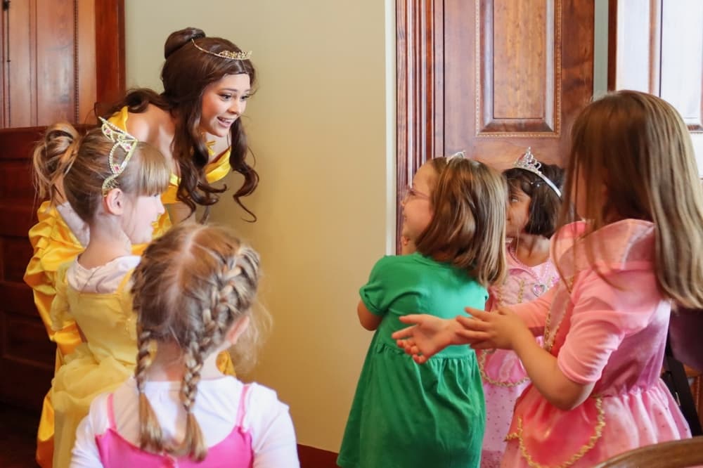 an adult dressed as a princess meets with children dressed as princesses