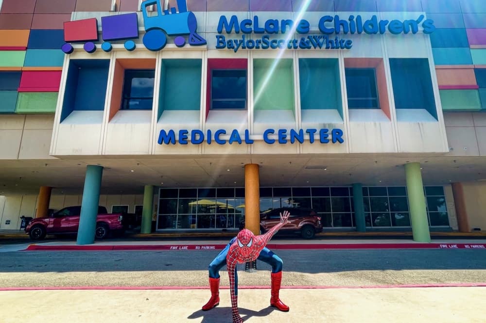 Spider-Man does a superhero pose outside a children's hospital