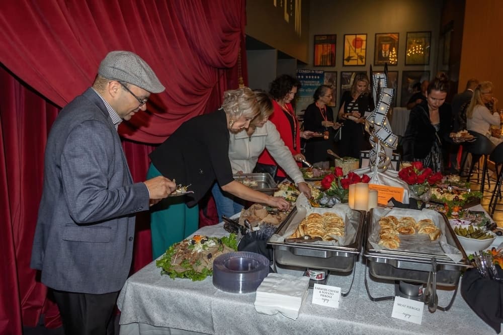 People gather around a table of food during a reception at a previous Austin Polish Film Festival.