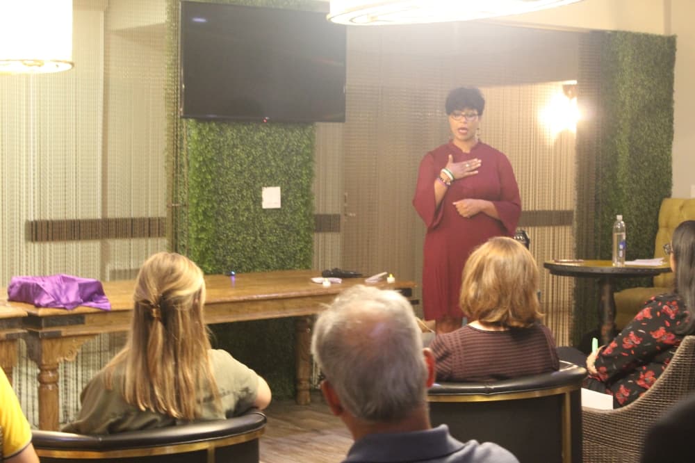 several people in chairs watch a woman speaking