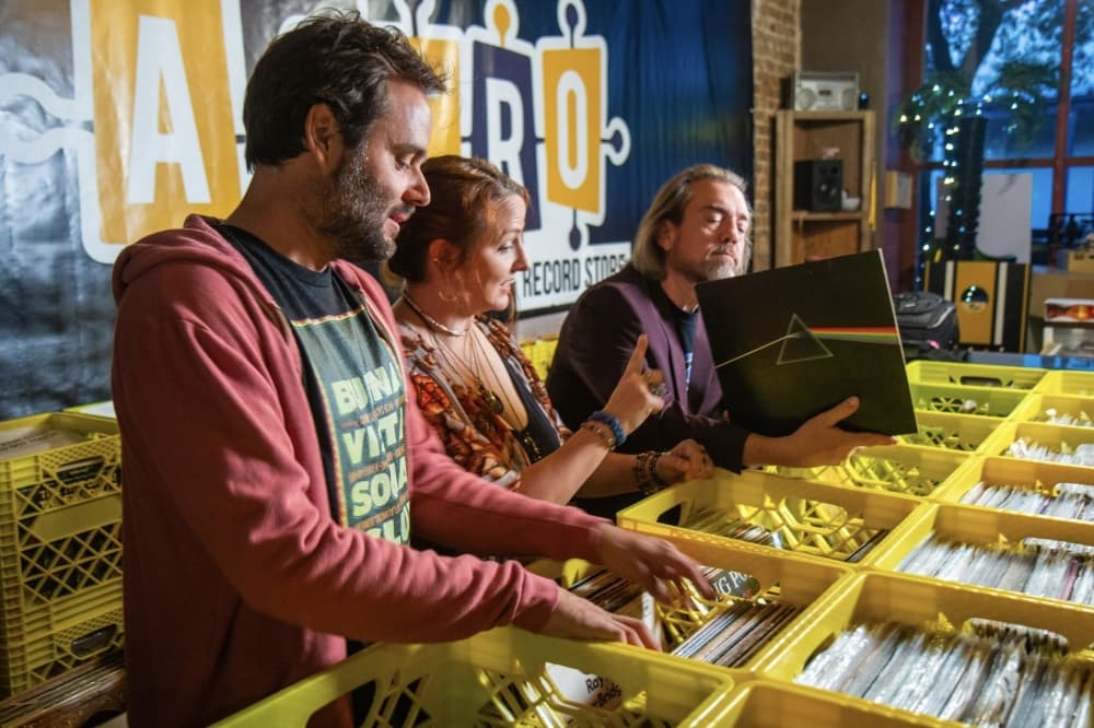 Three adults look at records in a store.