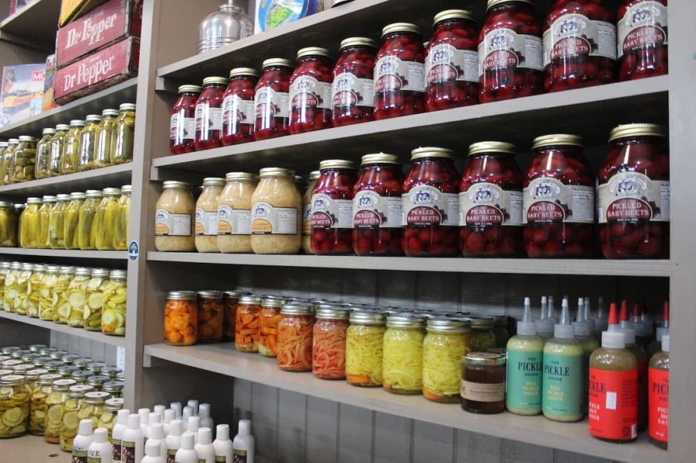 Pickled baby beets, saerkraut and dill pickle sauce on a shelf. (Amira Van Leeuwen/Community Impact)