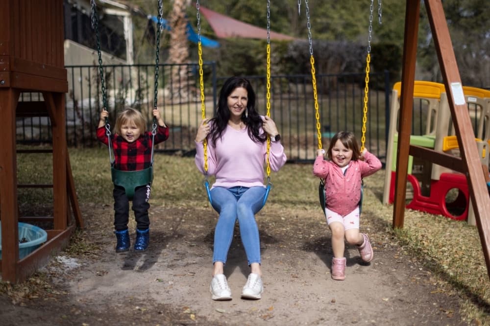 a woman and two children on swings in a swing set