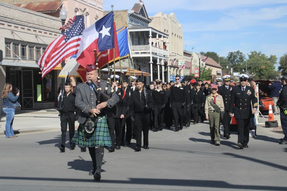 Men and women in uniform marching down Main Street.