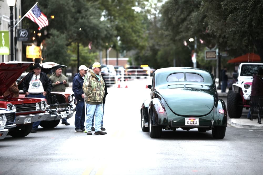 A classic car driving down a street.