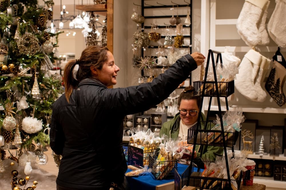 A person chooses an item to look at inside a shop with a Christmas tree in the background.