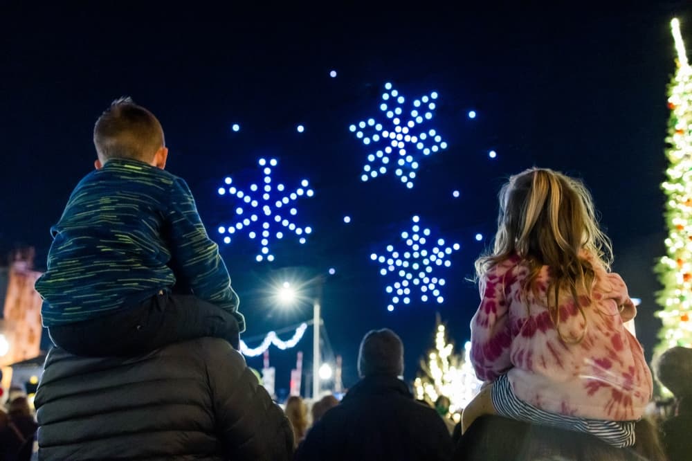 Drones make snowflake figures over an audience