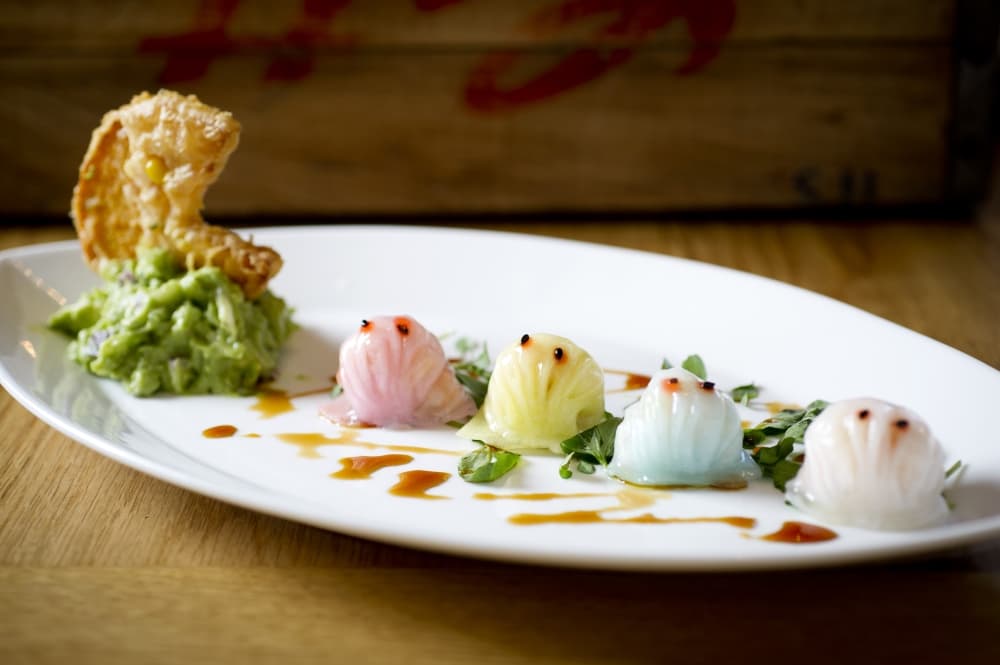 A white plate holds colorful dumplings shaped like Pac-Man characters.
