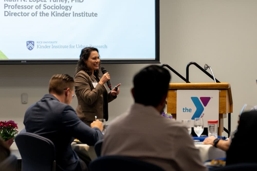 The photo shows a YMCA leader speaking at an event. 