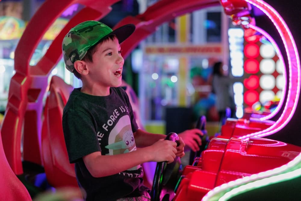 a child playing a driving arcade game