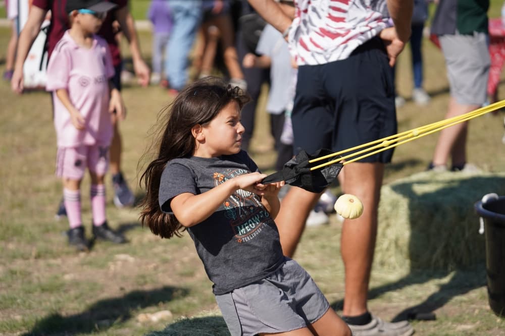 A child launches a small white pumpkin outside.