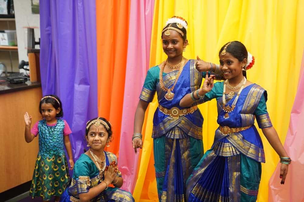 Four children are dressed in traditional Indian clothing and pose for a photo.