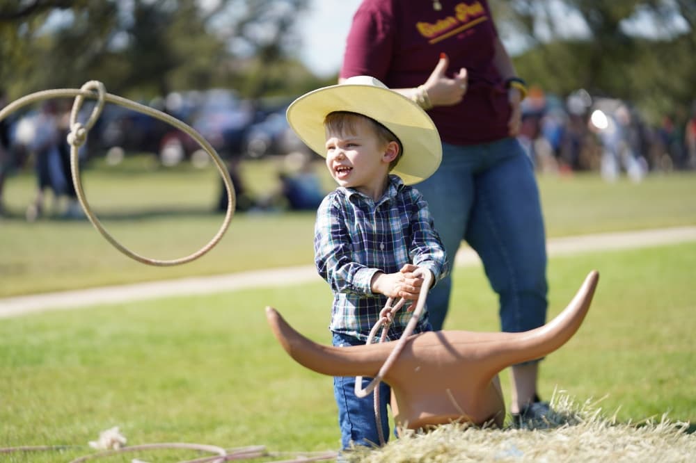 A child lassos a fake longhorn outside.