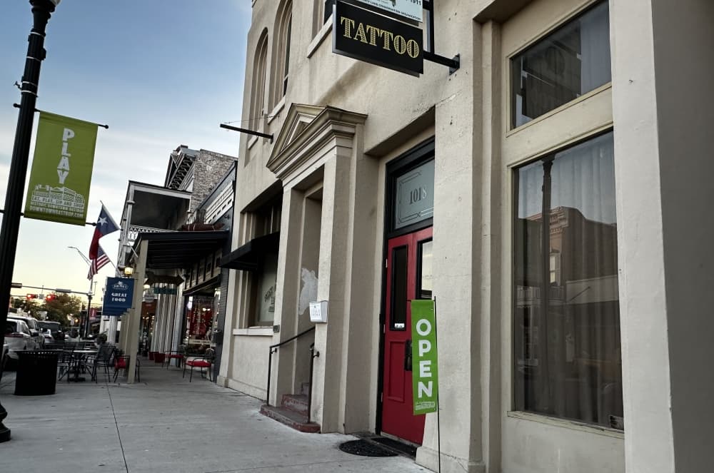 The outside of the tattoo shop with an "open" sign.