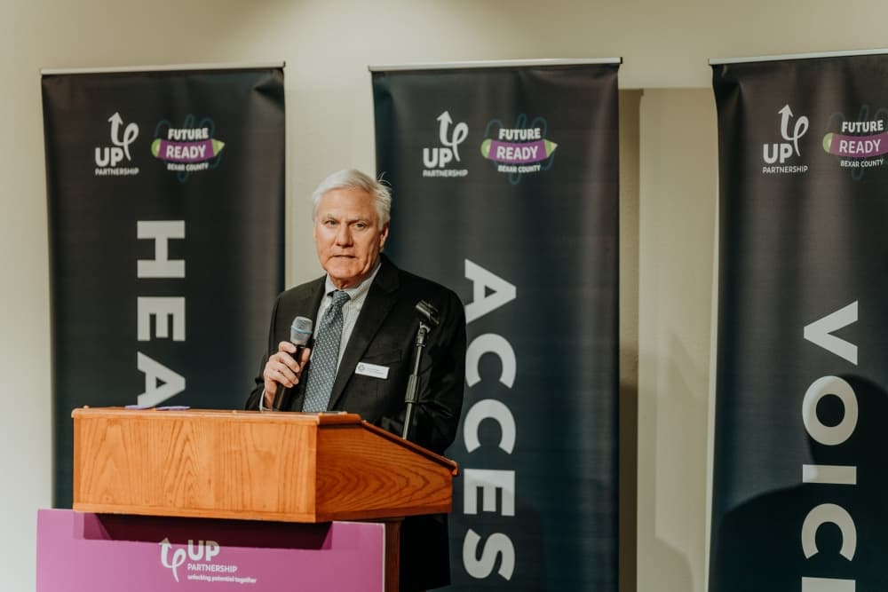 man stands at speaks into a microphone at a podium