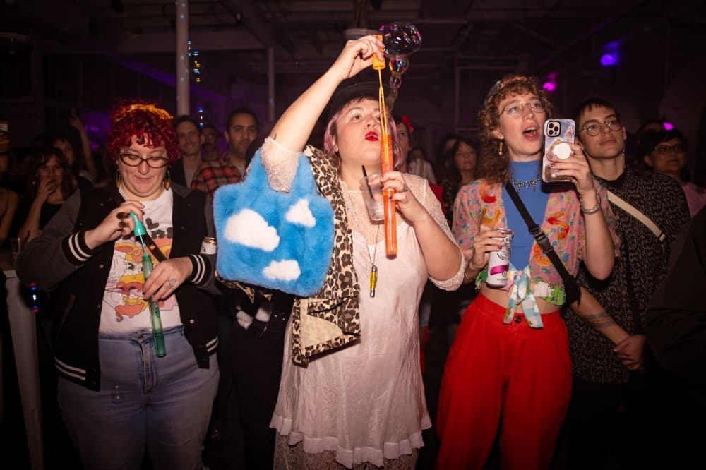 A small group of people blow bubbles and take a photo with their phone inside one of the venues.