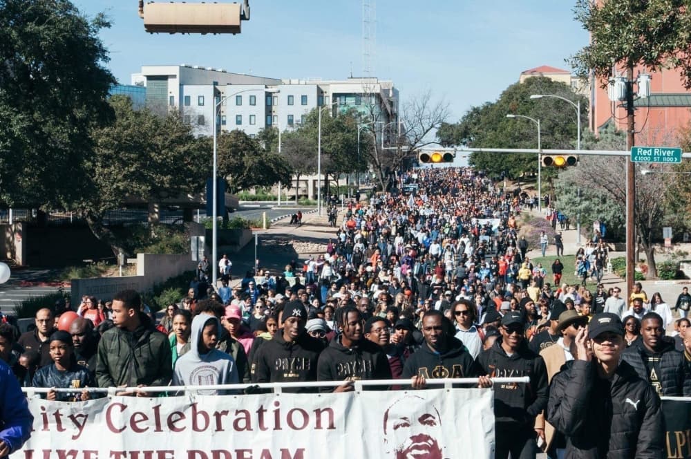 Photo shows a large group of people holding an MLK Day banner outside in Austin.