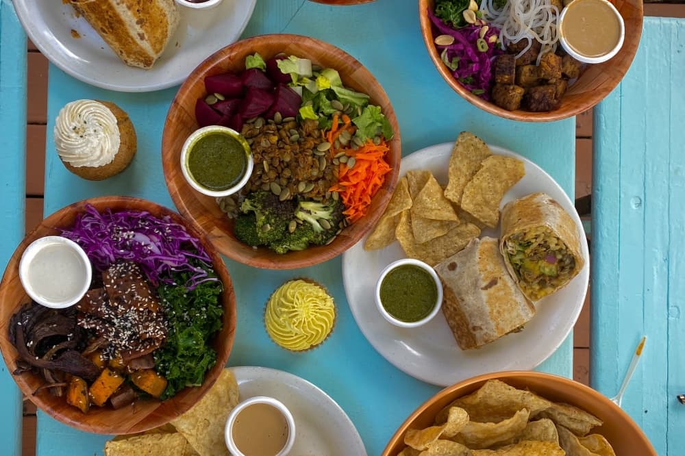 A blue table holds a variety of vegan dishes.