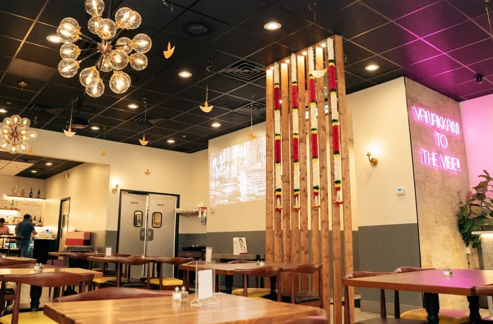 A look at the inside of the restaurant with tall ceilings and neon signs.