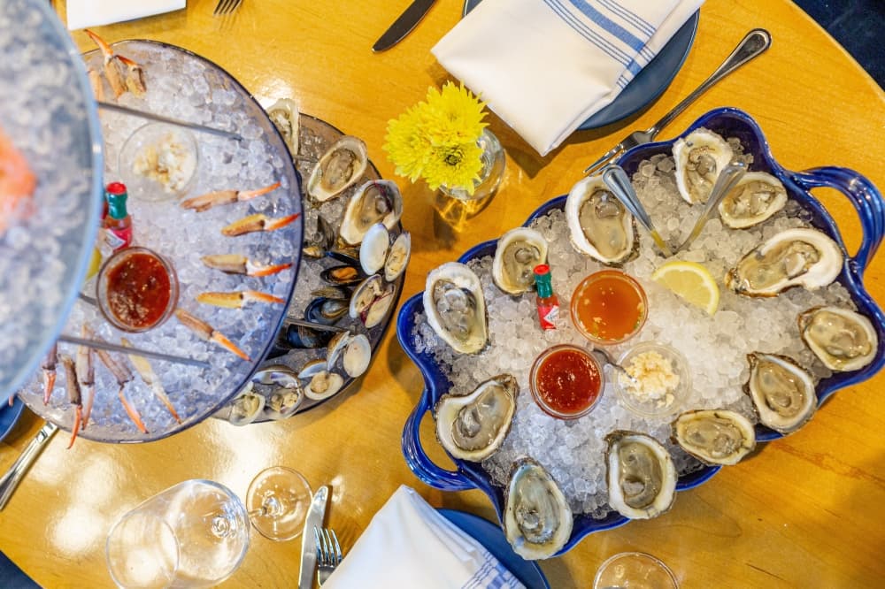 A table holds a tray of oysters and a seafood tower.