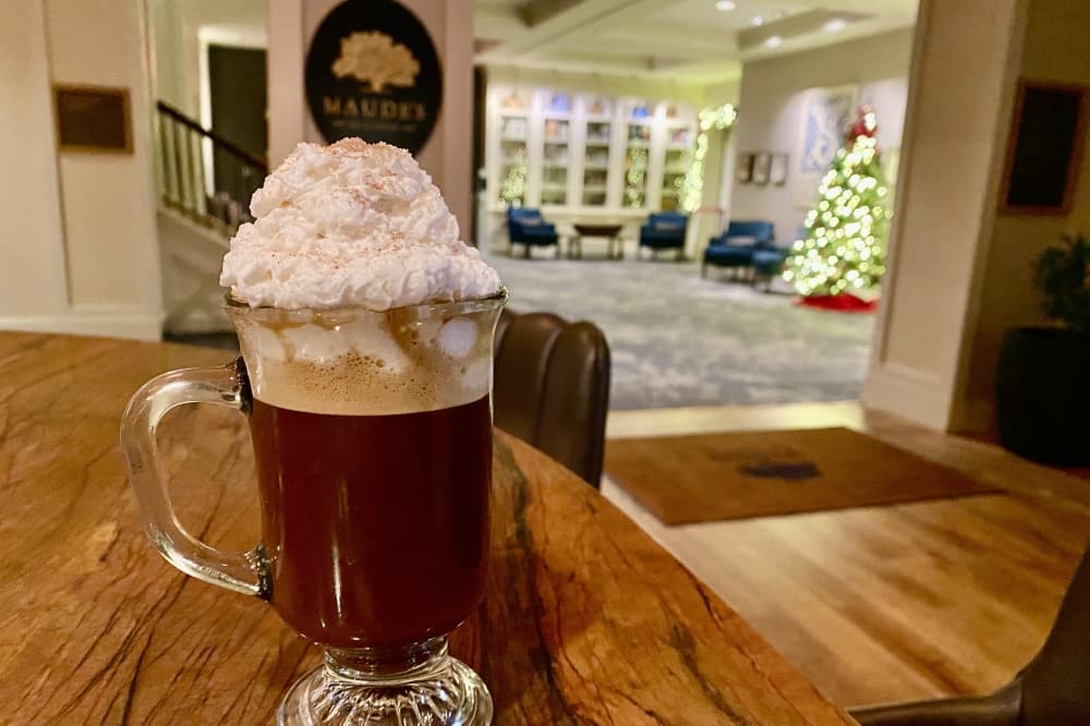 A hot chocolate in front of a sign reading "Maude's."