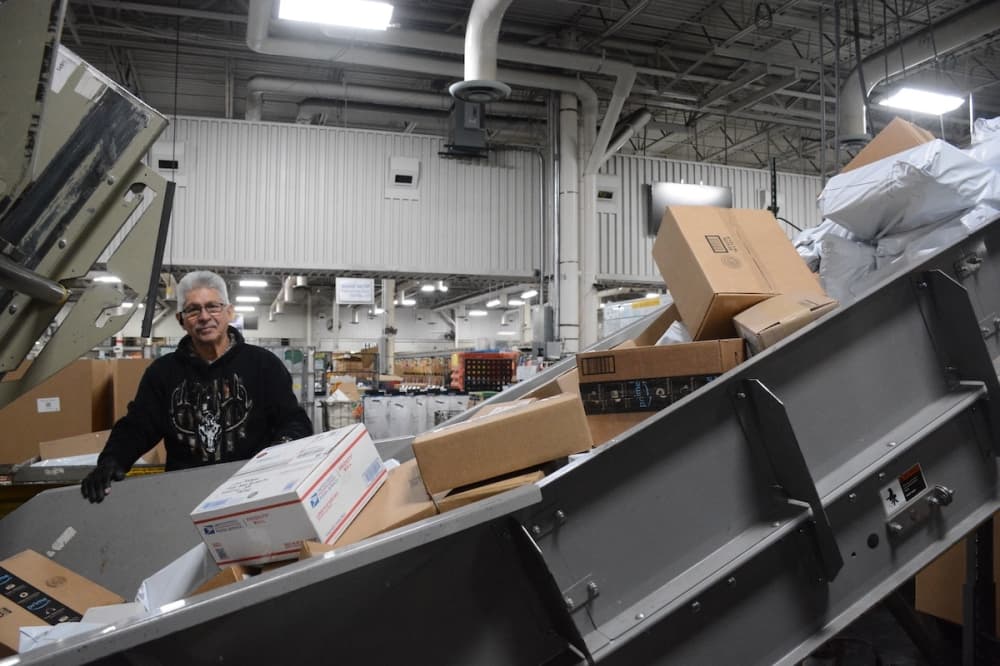 Worker making sure packages are fed cleanly into a conveyor belt