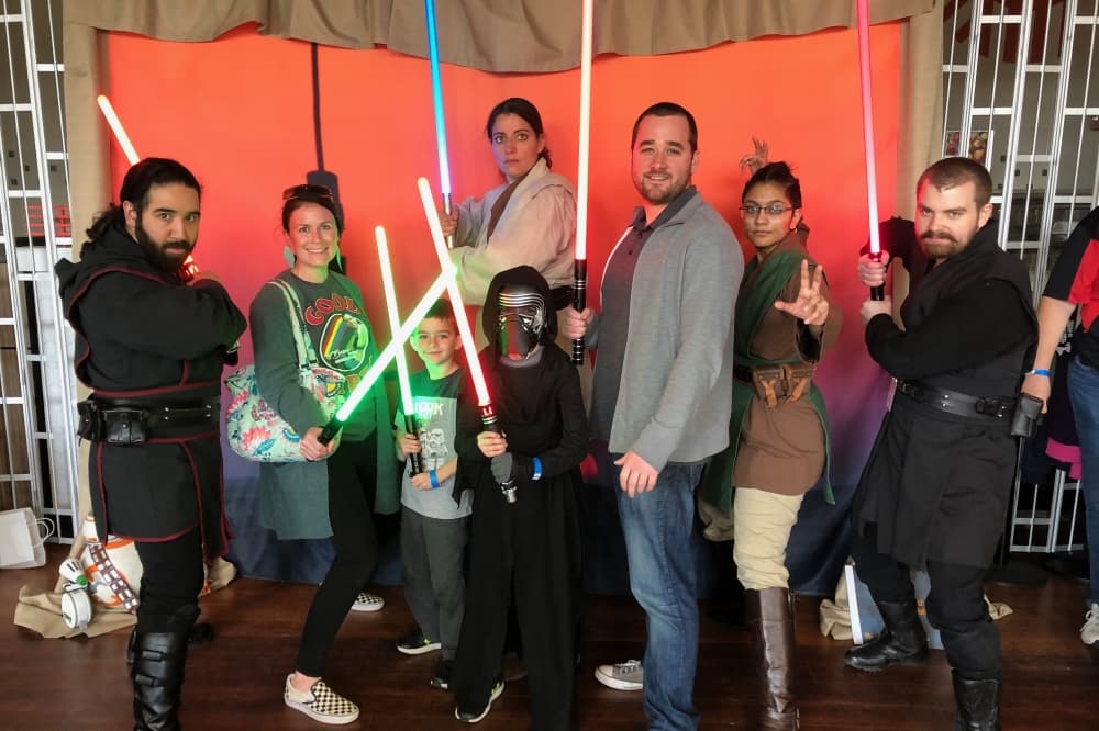 people pose with light sabers