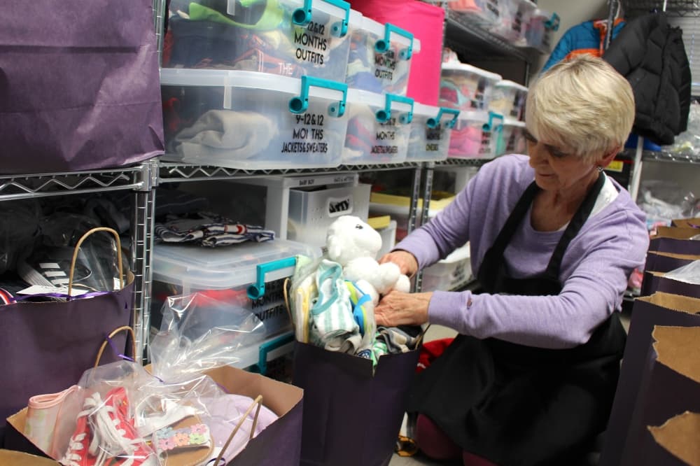 C.J. Works has been a volunteer at Clothed by Faith for nine years. She places items in a bag for young clients. (Kelly Schafler/Community Impact)