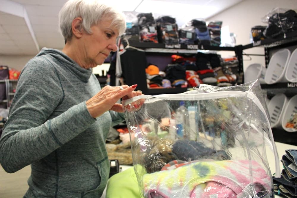 Linda Smith has been a volunteer at Clothed by Faith for seven years. Smith folds and packs donated sweaters that will later be given to families. (Kelly Schafler/Community Impact)