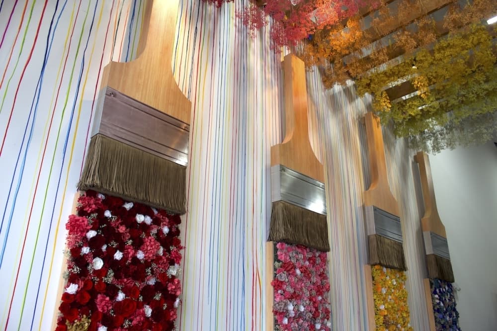 Wall art of large paint brushes above different colored roses.