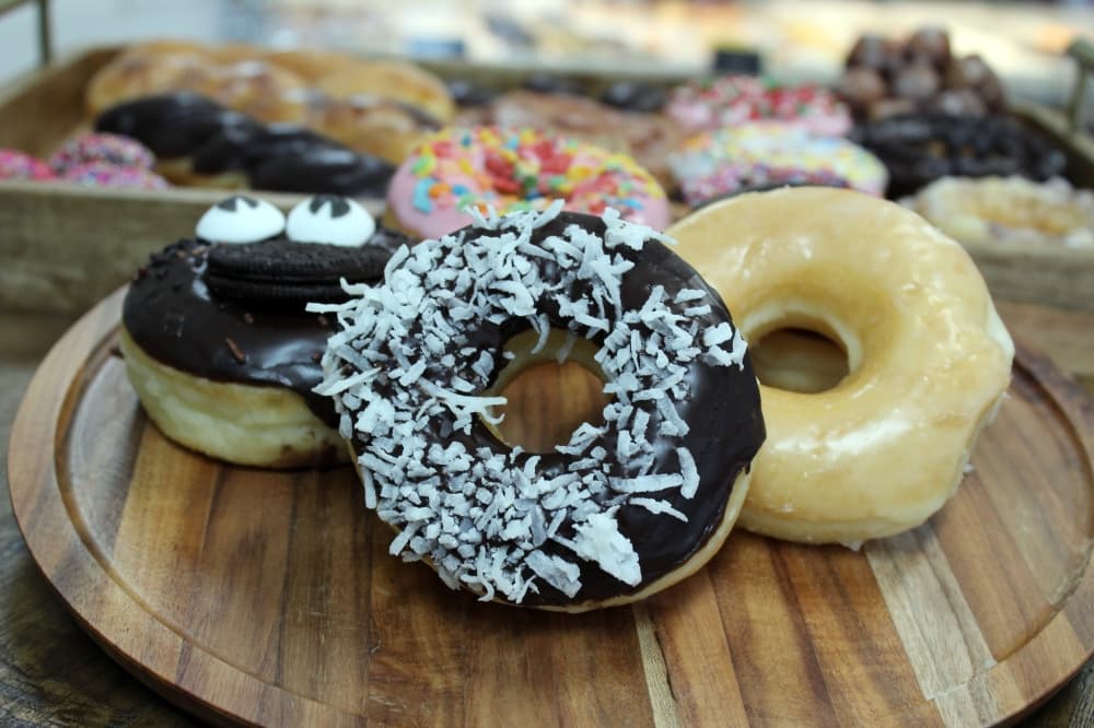 An arrangement of different types of donuts on a wooden tray.