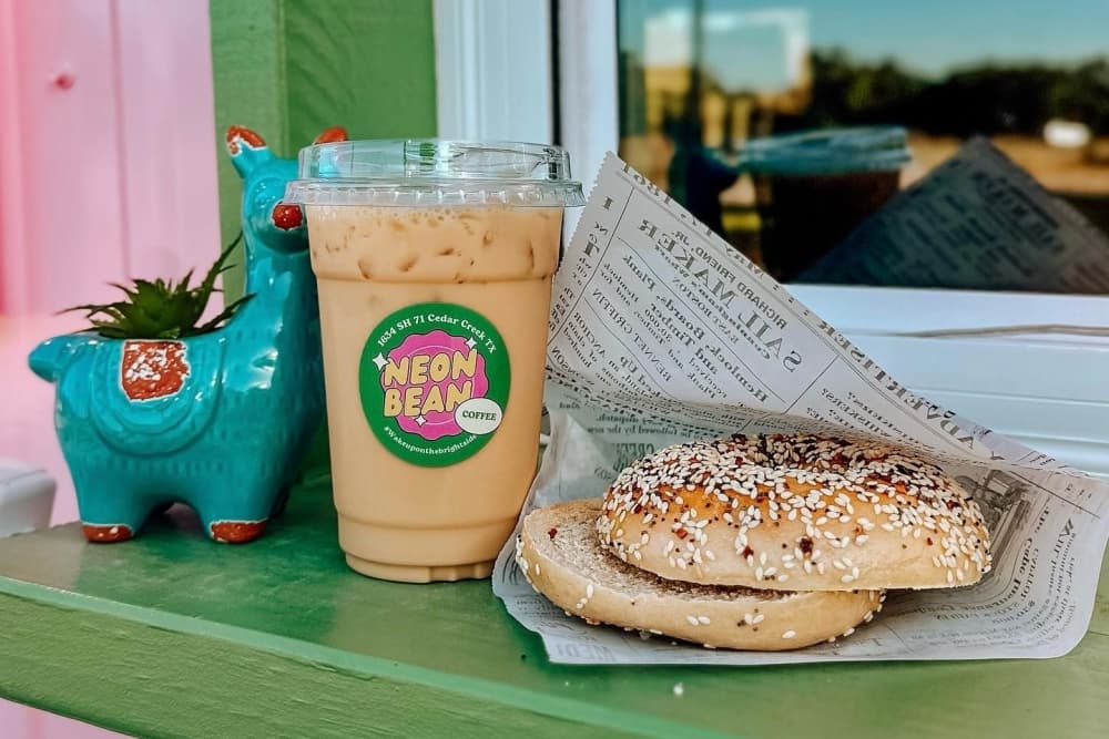 A bagel and coffee are perched on the ledge of the kiosk.