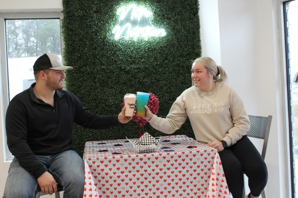 Owners sit on table and cheers with a smoothie and loaded tea