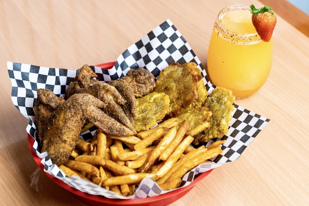 Chicken wings, fries and tostones with cocktail on the side.