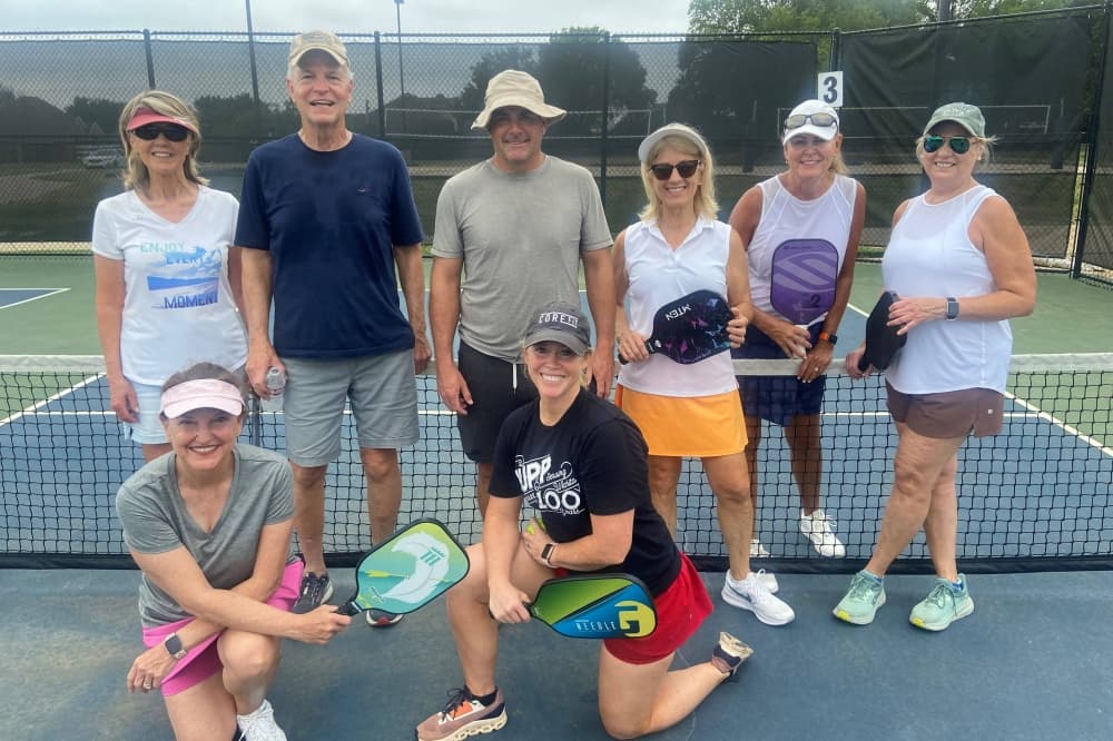 People standing on pickleball court with rackets