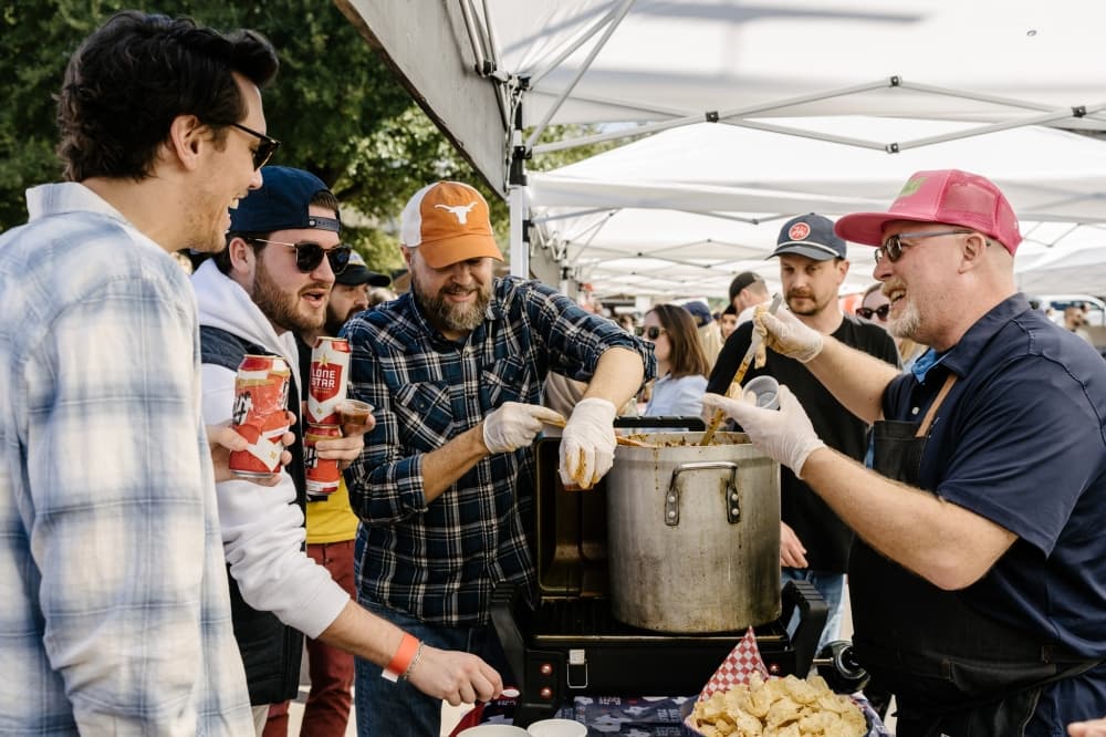 A group of people chat at a previous chili cookoff