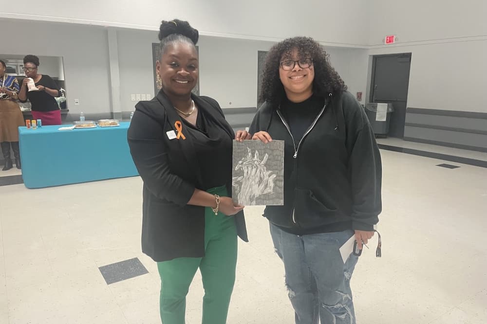 An artist stands with their painting as part of an art exhibit put on by Turning Point in Webster. (Courtesy Turning Point)