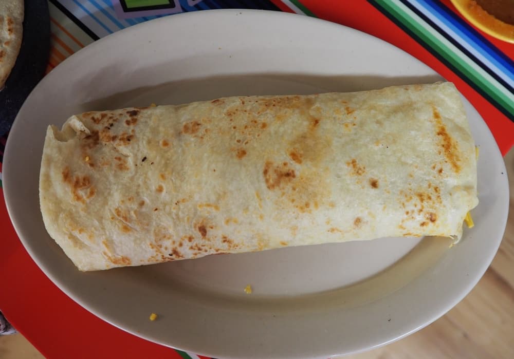 a large taco in a flour tortilla on a plate