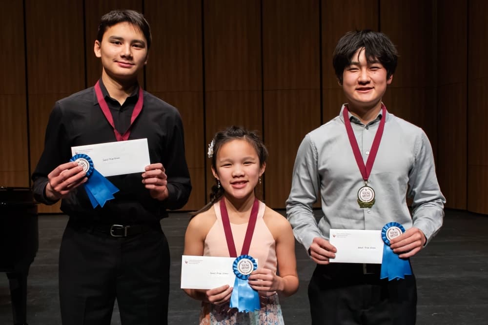 Two teen boys, one girl posing with ribbons around their necks