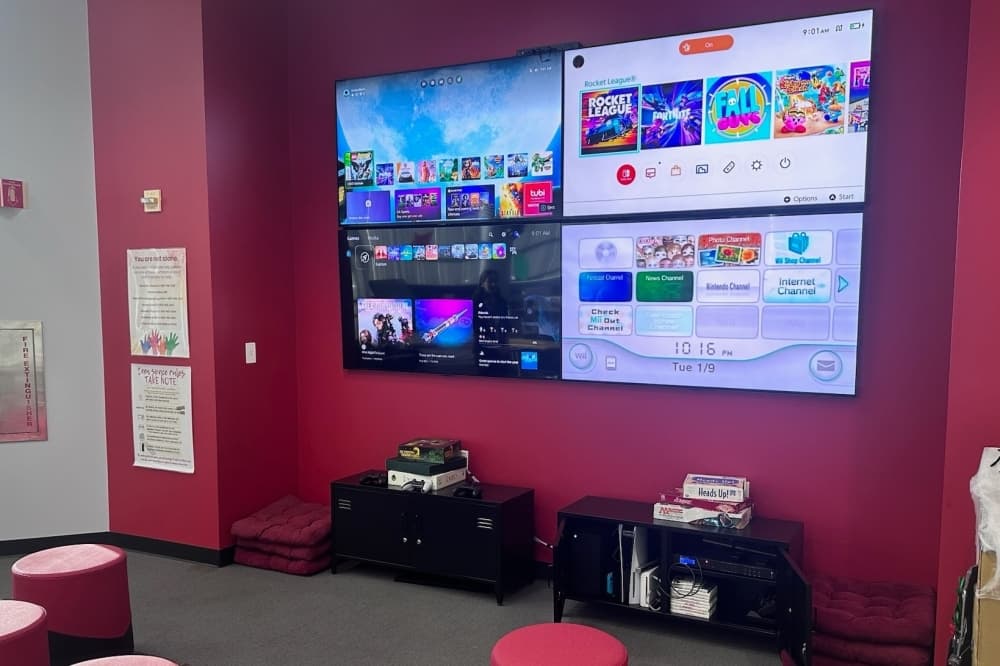 A wall of four TVs hooked up to various game consoles