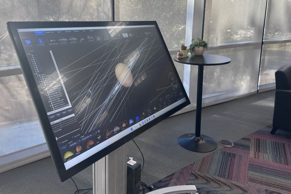 A digital touchscreen table showing the planet Saturn