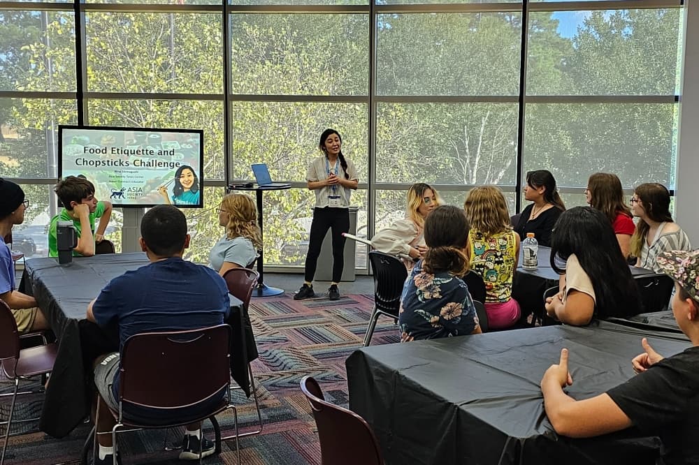 Teens sit at various tables for a library program