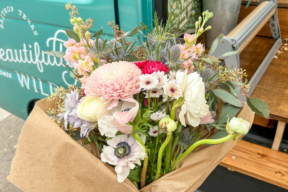 A bouquet of flowers is held up with the turquoise truck in the background.