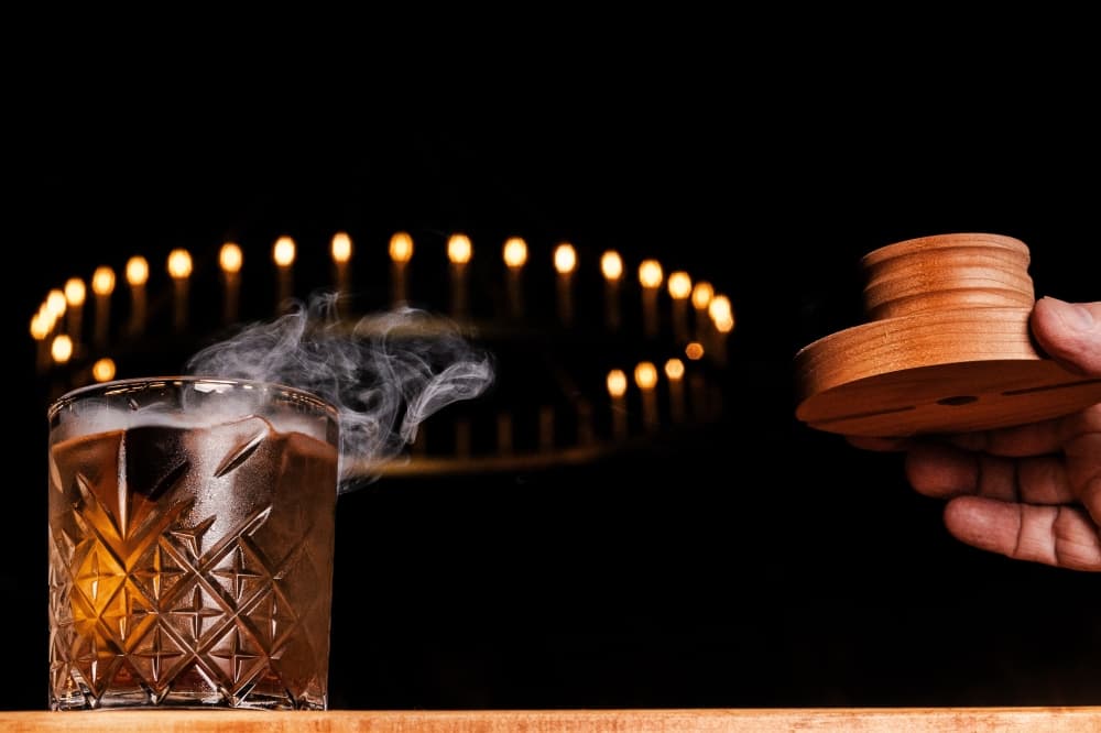 Smoke billows from a brown-colored cocktail.