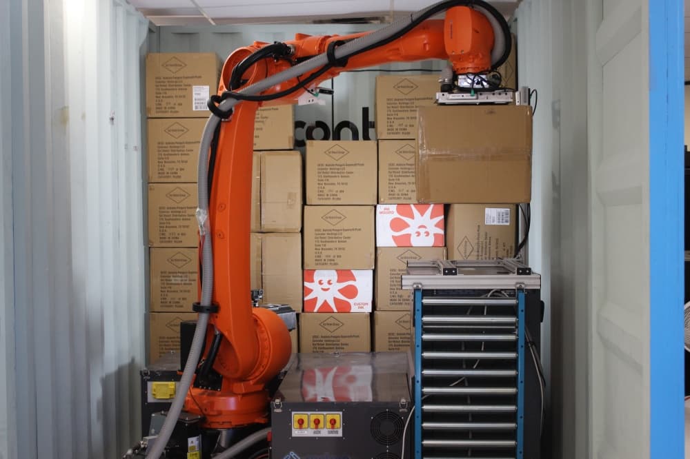 machine moving boxes onto conveyor belt