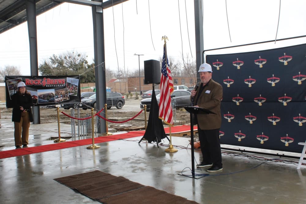 Dave Stevens speaks in front of Rock & Brews background