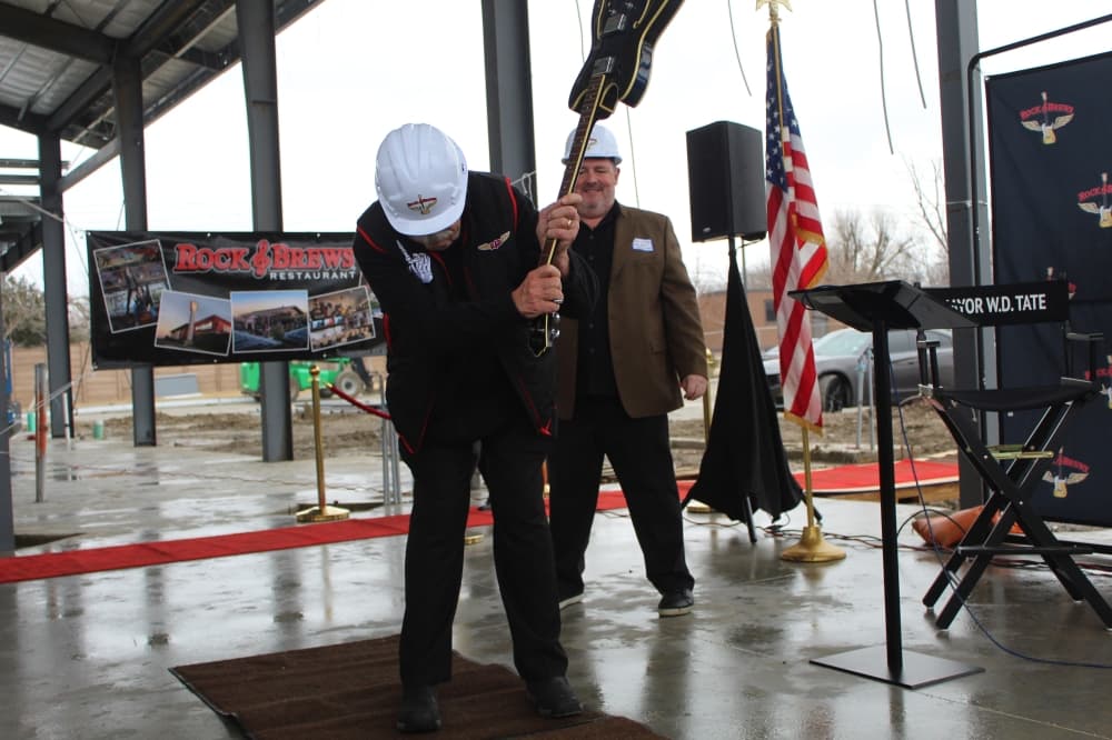 the mayor raises a guitar over his head ready to smash it