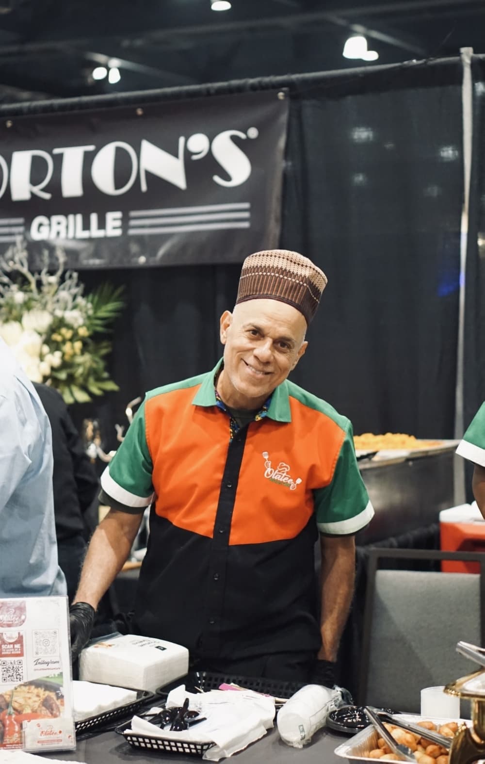 A chef smiles behind a selection of food